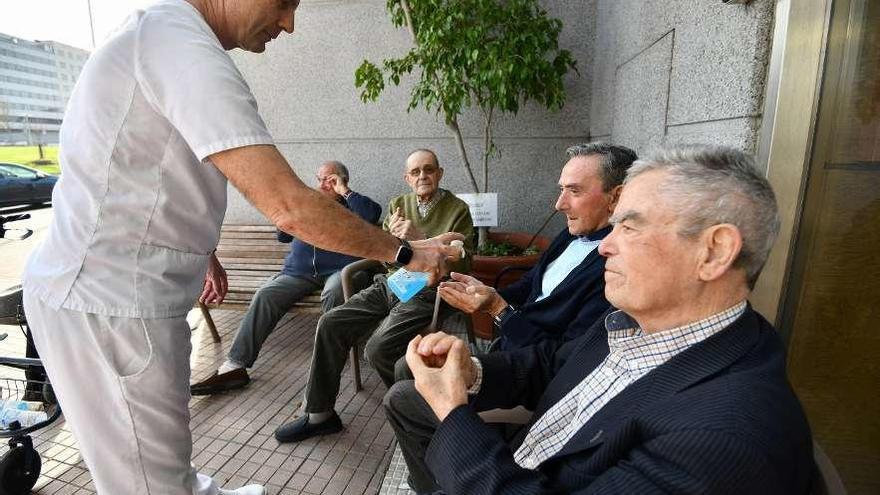 Un trabajador facilita gel hidroalcohólico a usuarios de la residencia de mayores de Campolongo. // G.S.