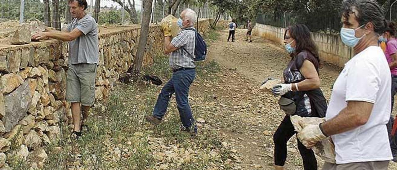 Integrantes de GADMA ponen las piedras grandes que han quedado en medio del camino sobre el muro.