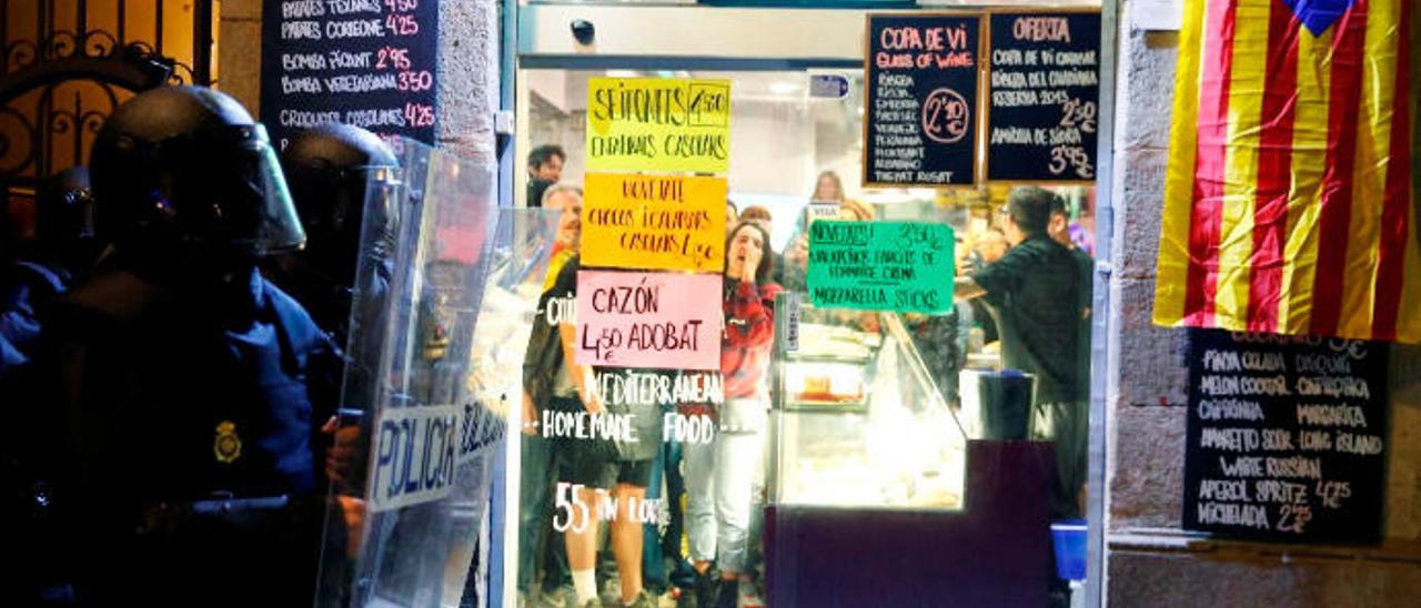 Un grupo de independentistas grita a los policías desde el interior de un ultramarinos de Barcelona.