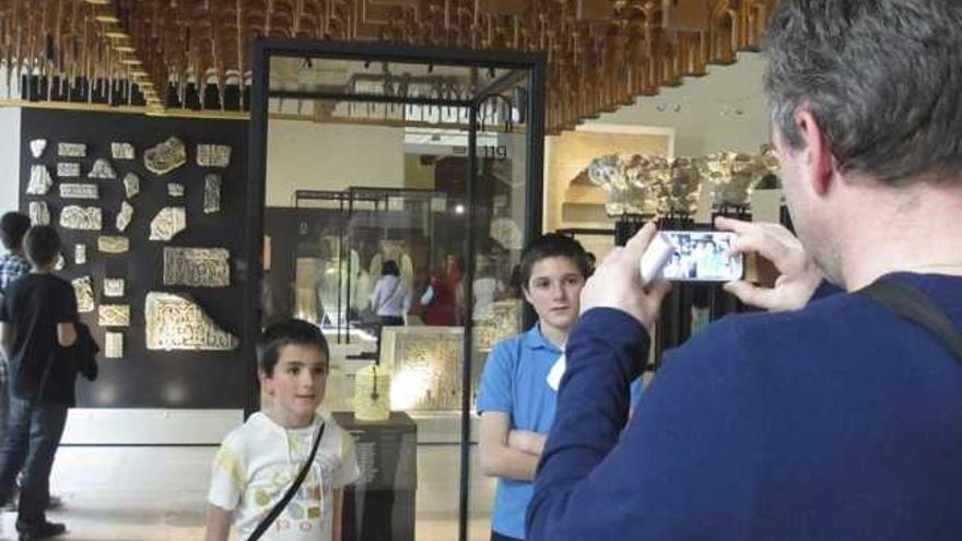 Un padre fotografía a sus hijos con el Bote de Zamora en el Museo Arqueológico de Madrid.