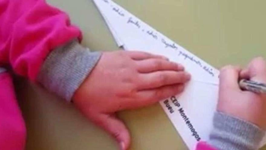 Unha alumna de Primaria de Beluso escribe os versos de Rosalía de Castro no avión de papel.