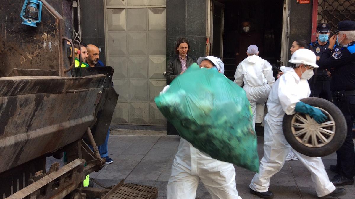 Operario retiran, hoy, basura acumulada en el patio de luces del edificio ocupado en el nº120 de la ronda de Nelle.