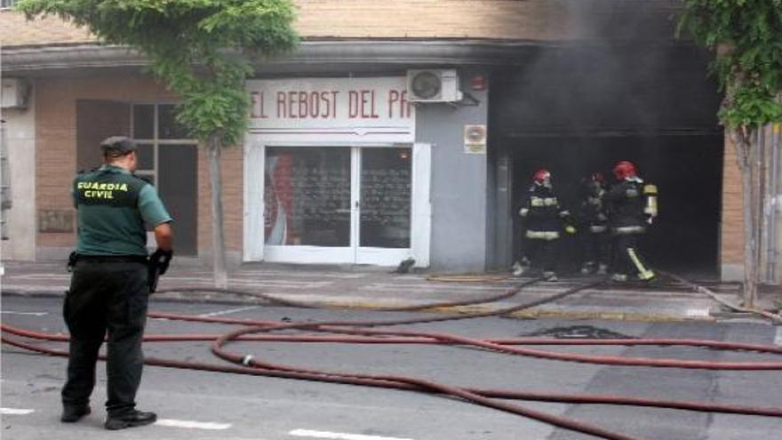 Dos bomberos acceden al interior del aparcamiento subterráneo bajo la mirada de un agente de la Guardia Civil.