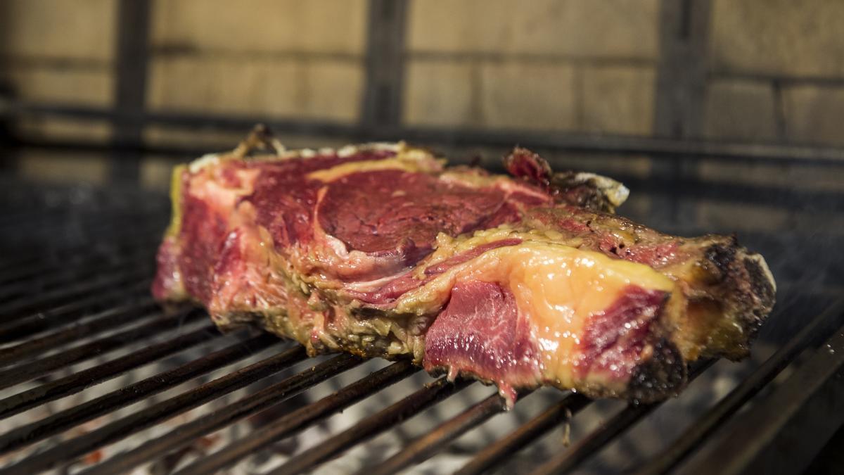 Un chuletón en la parrilla del asador.