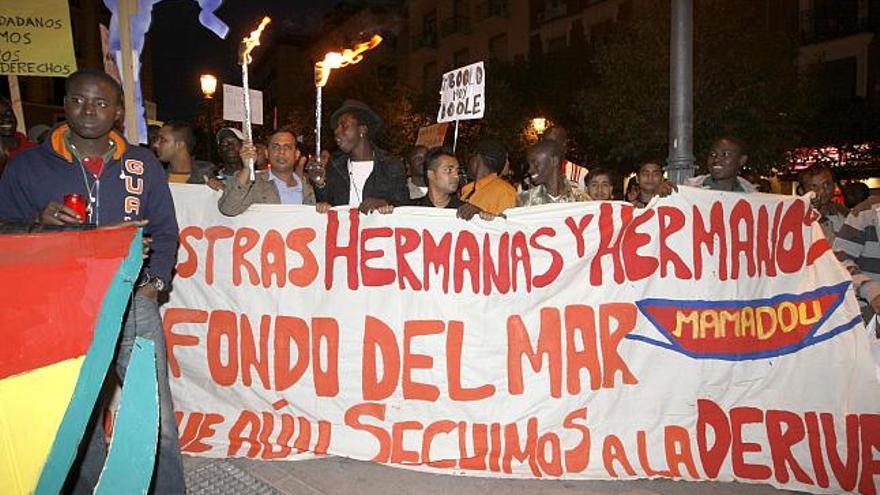 Varias personas durante la manifestación organizada por la Asociación Sin Papeles de Madrid, para homenajear a los fallecidos en el paso del Estrecho, a los &quot;detenidos&quot; y a los &quot;que sobreviven al llegar al destino, todavía a la deriva&quot;, que se ha celebrado hoy en Madrid. EFE/Manuel H. de León