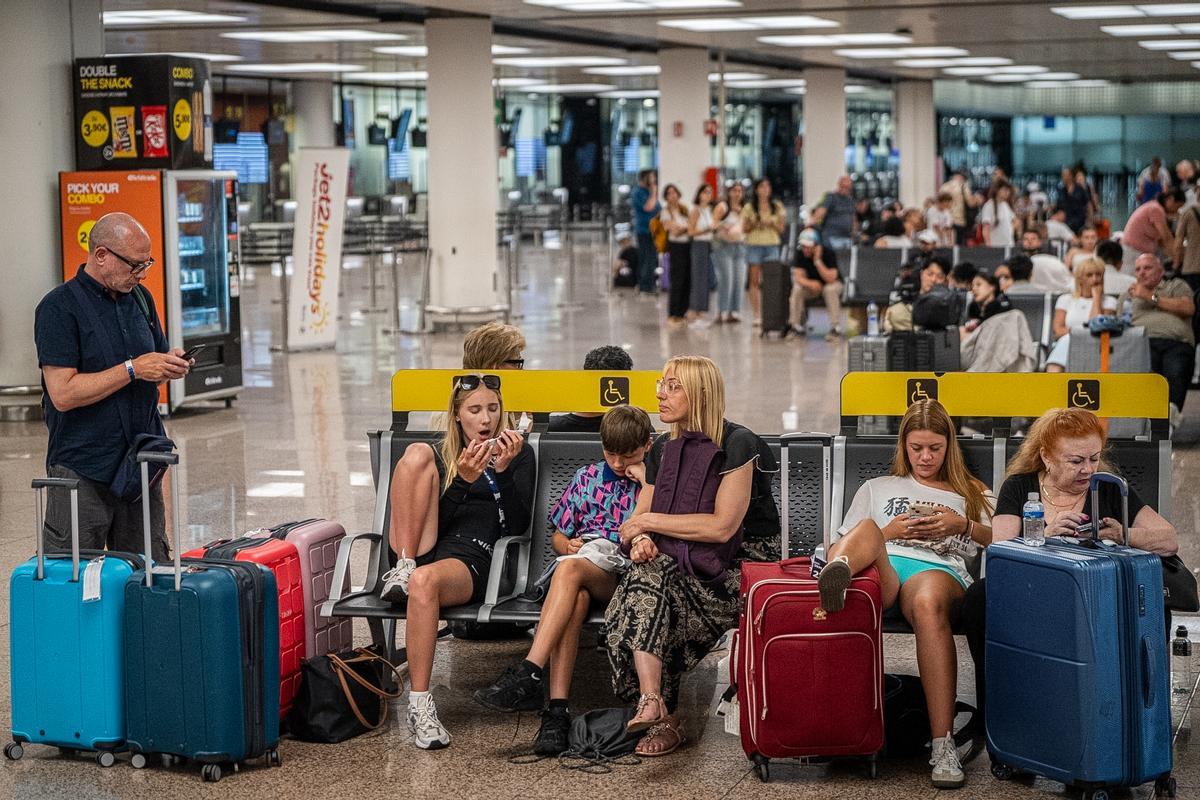 Varios pasajeros esperan sus viajes en la terminal T2 del aeropuerto de Barcelona-El Prat.