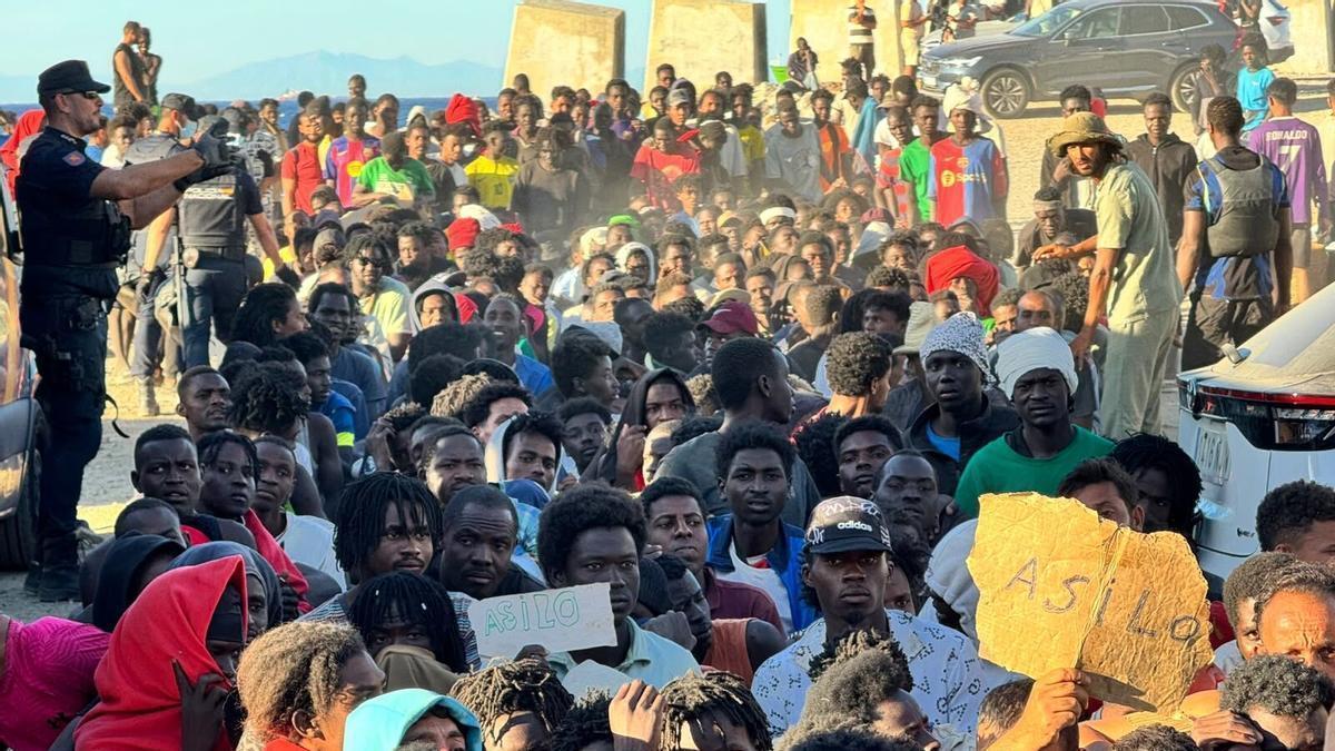 Inmigrantes asentados en Ceuta con efectivos policiales organizando la zona.