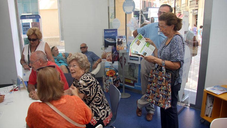 Personas mayores son atendidas en una agencia de viajes de Málaga para formalizar un viaje a través del programa del Imserso.