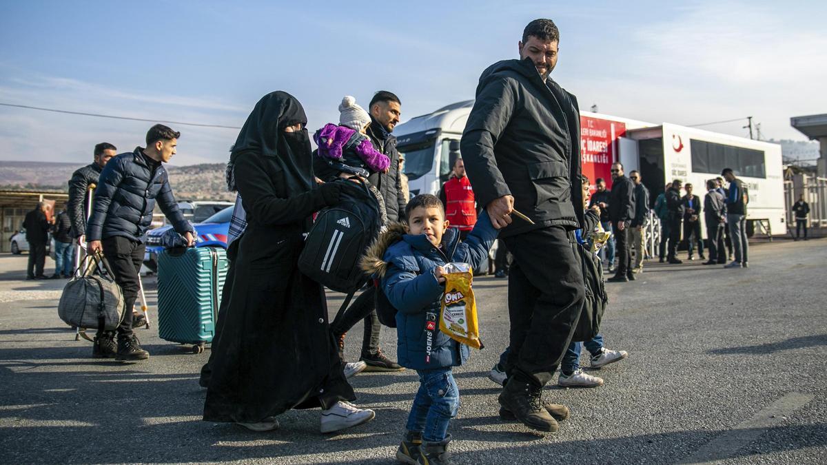Refugiados sirios llegan al cruce fronterizo de Cilvegözu, donde aguardan también camiones para pasar de Turquía a Siria.