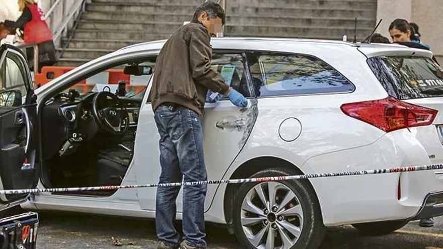 Un policía busca huellas en el taxi donde se cometió la agresión.