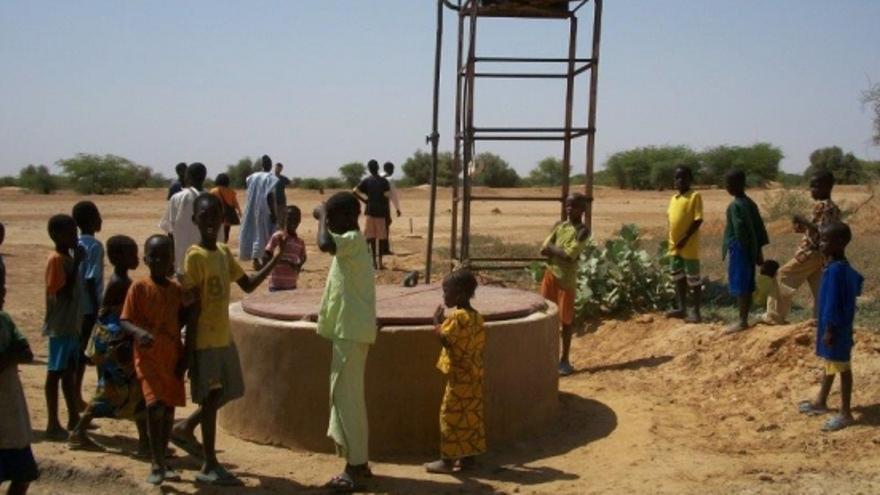 Varios niños fotografiados junto a un pozo de agua, creado a partir de un proyecto de cooperación internacional.