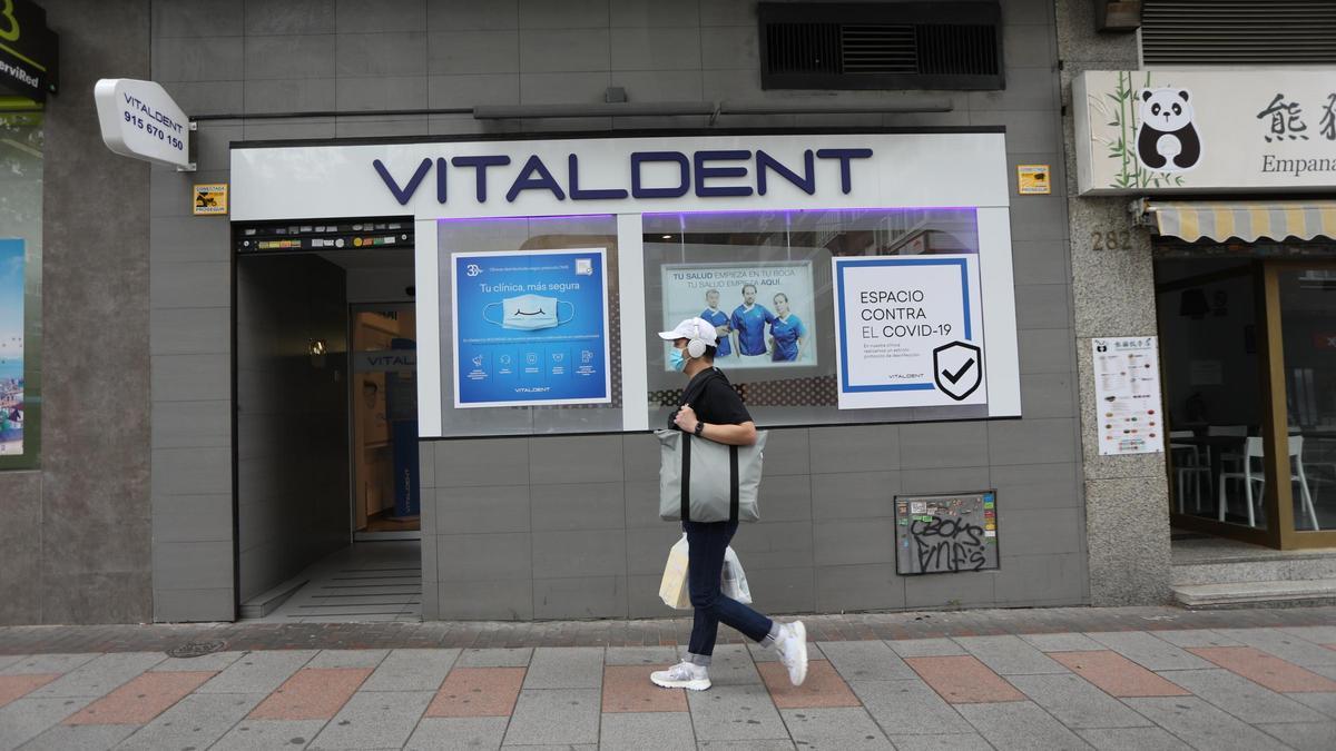 Un hombre con mascarilla pasa junto a la entrada de una clínica Vitaldent.