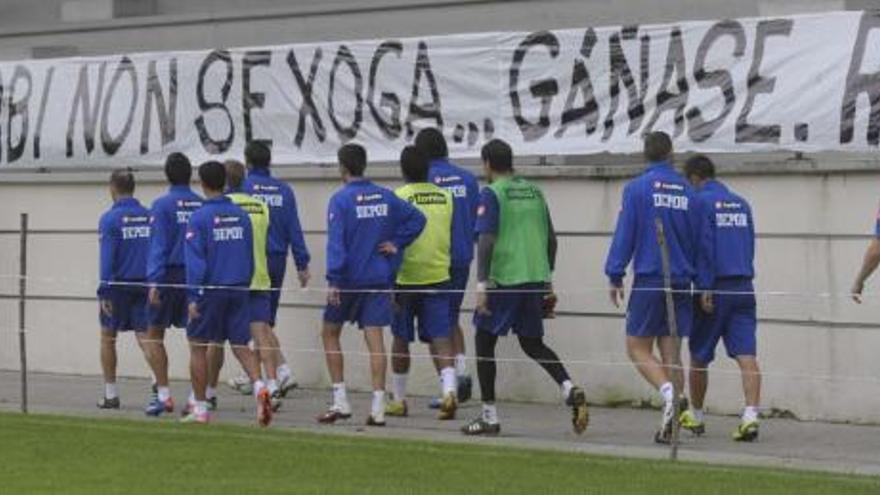 Los jugadores blanquiazules, retirándose ayer hacia los vestuarios con el tifo colocado en las gradas que reza: &#039;O derbi non se xoga... gáñase&#039;. / carlos pardellas