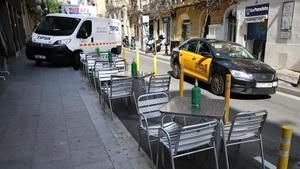 Una furgoneta de reparto sobre la acera, en Torren de l’Olla, junto a una terraza en la calzada.