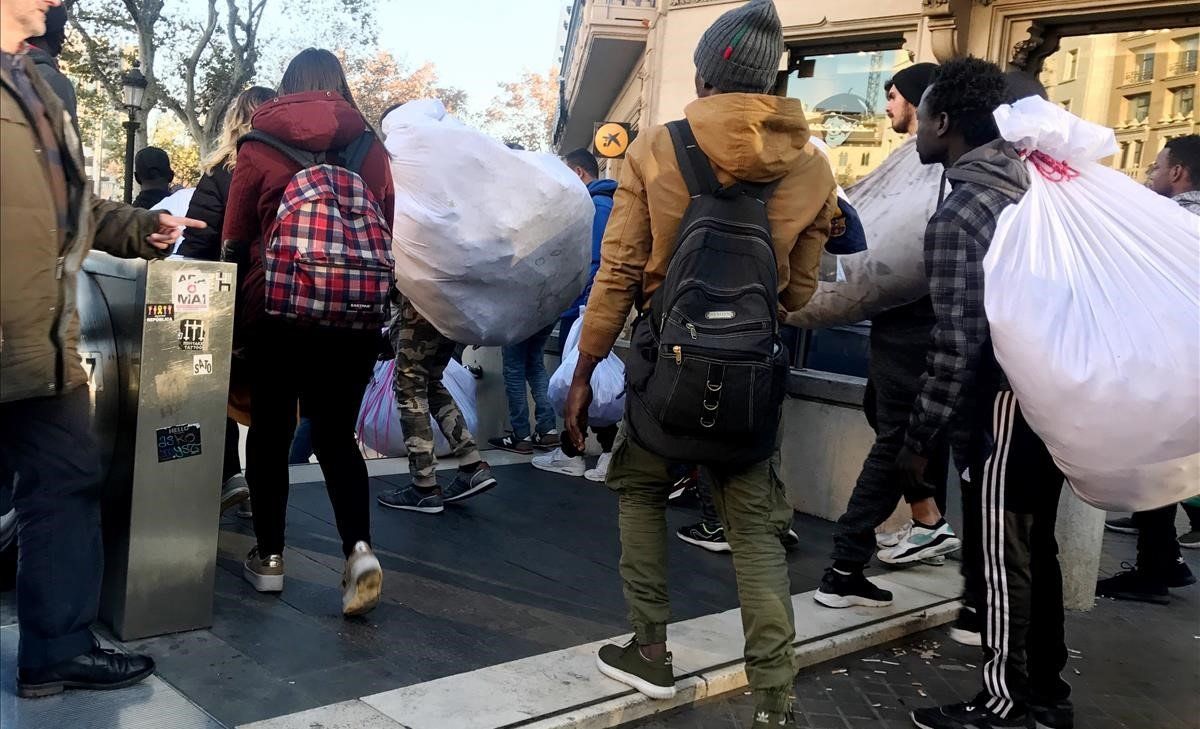 Venta ambulante en la Plaça Catalunya. En la foto vendedores ambulantes se meten en la estación de tren por la presencia de la Guardia Urbana en la calle.