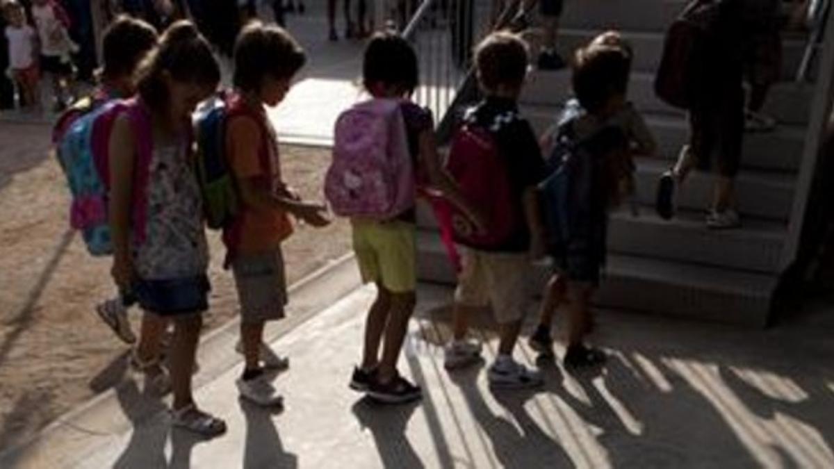 Un grupo de niños esperan en la puerta de un colegio.