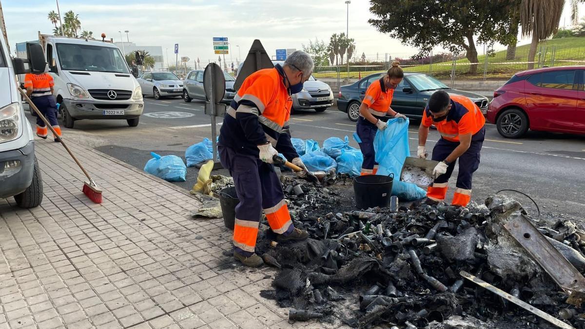 Trabajadores de limpieza retiran restos de un contenedor quemado en la Vega de San José.