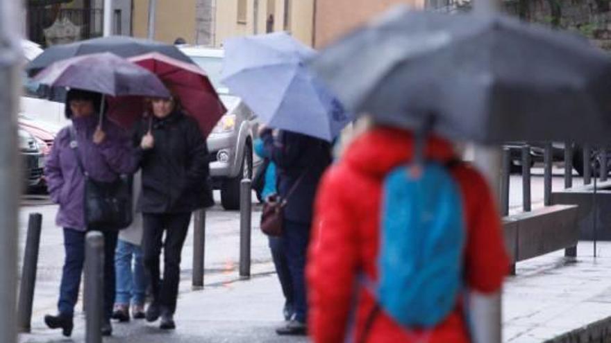 Un grup de vianants es protegia de la pluja amb paraigües ahir a la tarda a Girona.