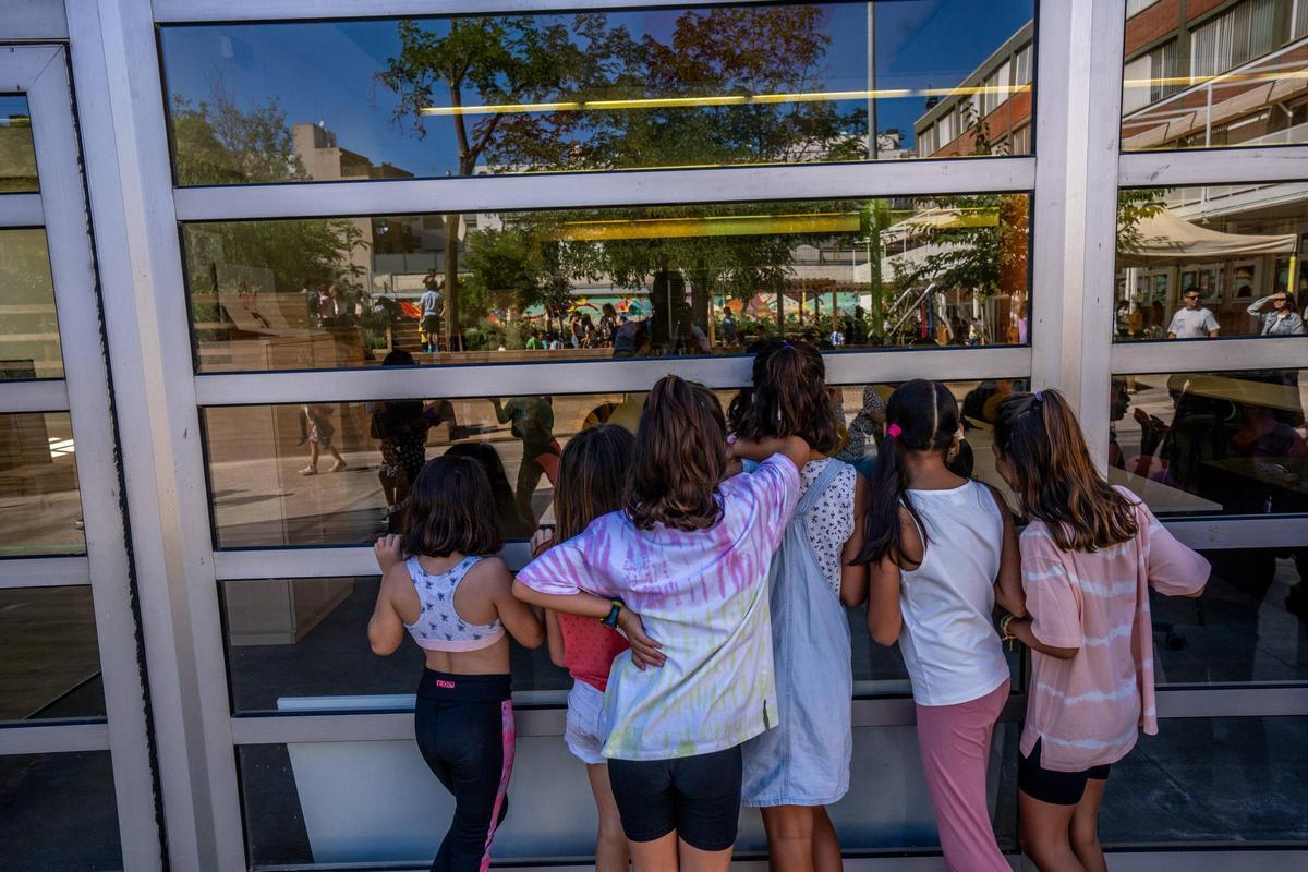 Un grupo de niñas se asoma por una cristalera de su escuela el primer día de clase, este lunes.