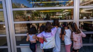 Un grupo de niñas se asoma por una cristalera de su escuela el primer día de clase, este lunes.