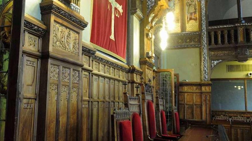 La sala de la Constitución de la Junta del Principado, durante una sesión de puertas abiertas al público, con la Cruz de la Victoria sobre fondo rojo.