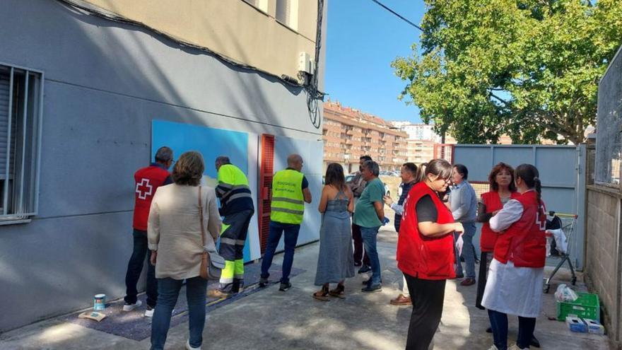 Voluntarios pintan el mural sobre el agua.