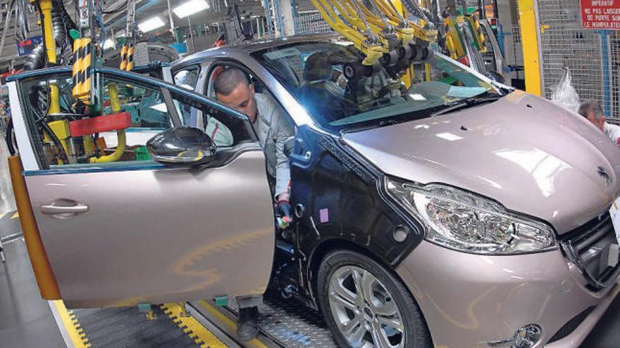 Un trabajador de PSA Peugeot Citroën manipula el nuevo Peugeot 208 en la planta de Poissy.  // D. Pizzalla