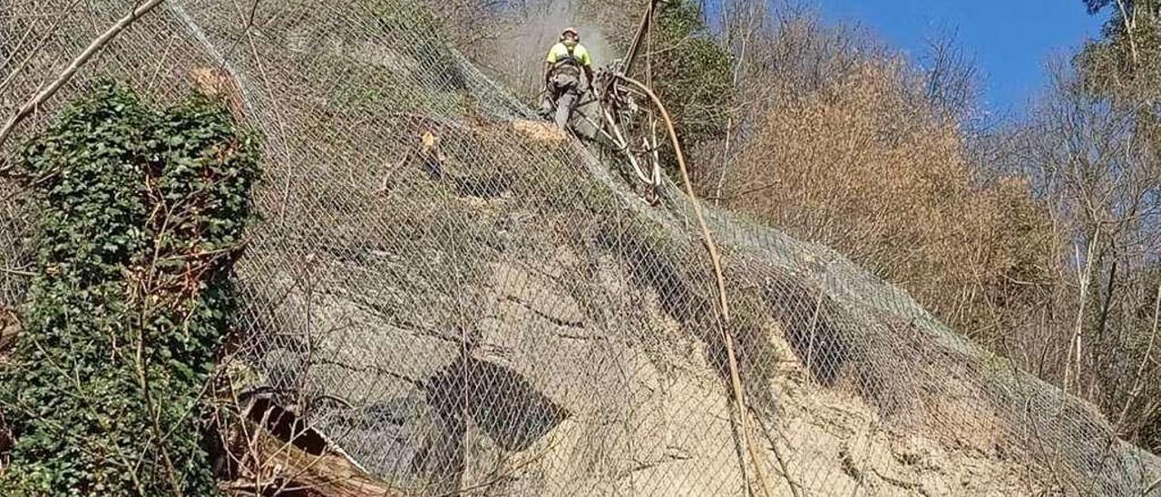 Un operario en lo alto de la ladera, ahondando para la instalación de la malla.