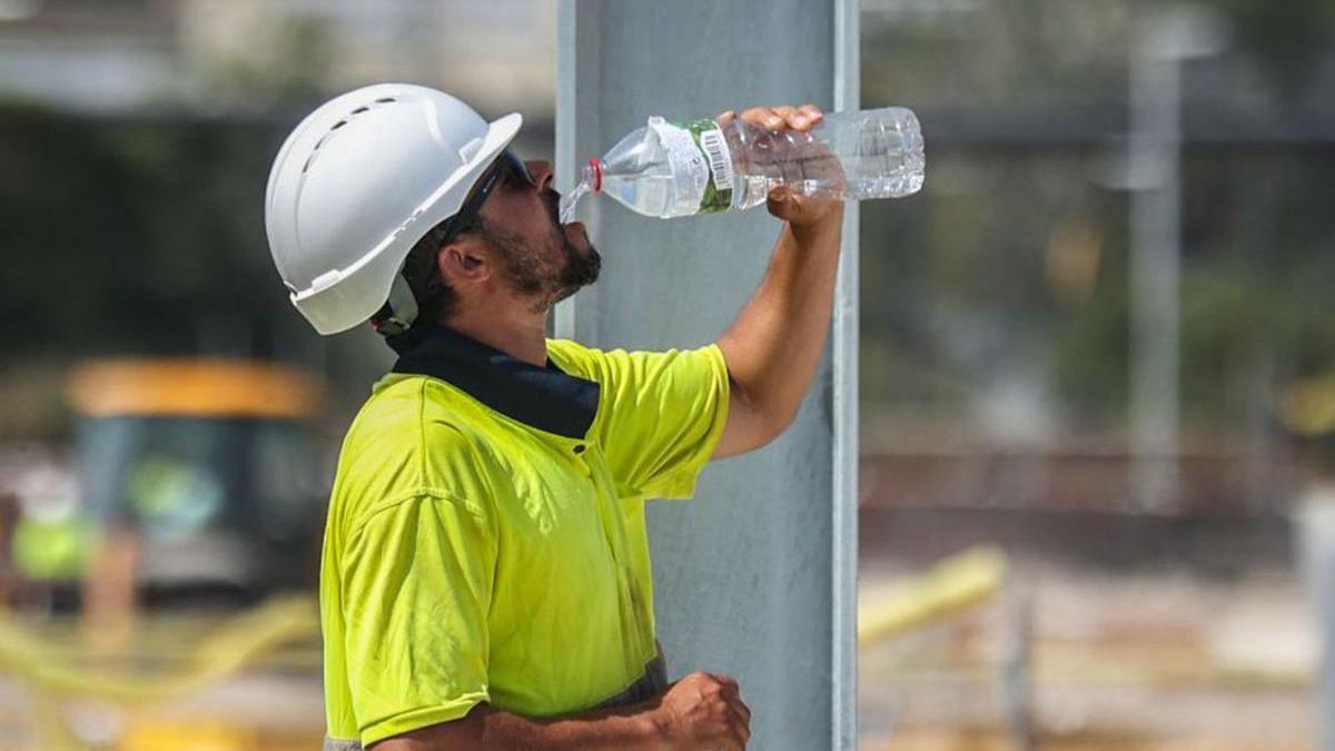Un treballador de la construcció beu aigua per combatre la calor.  | JORDI OTIX