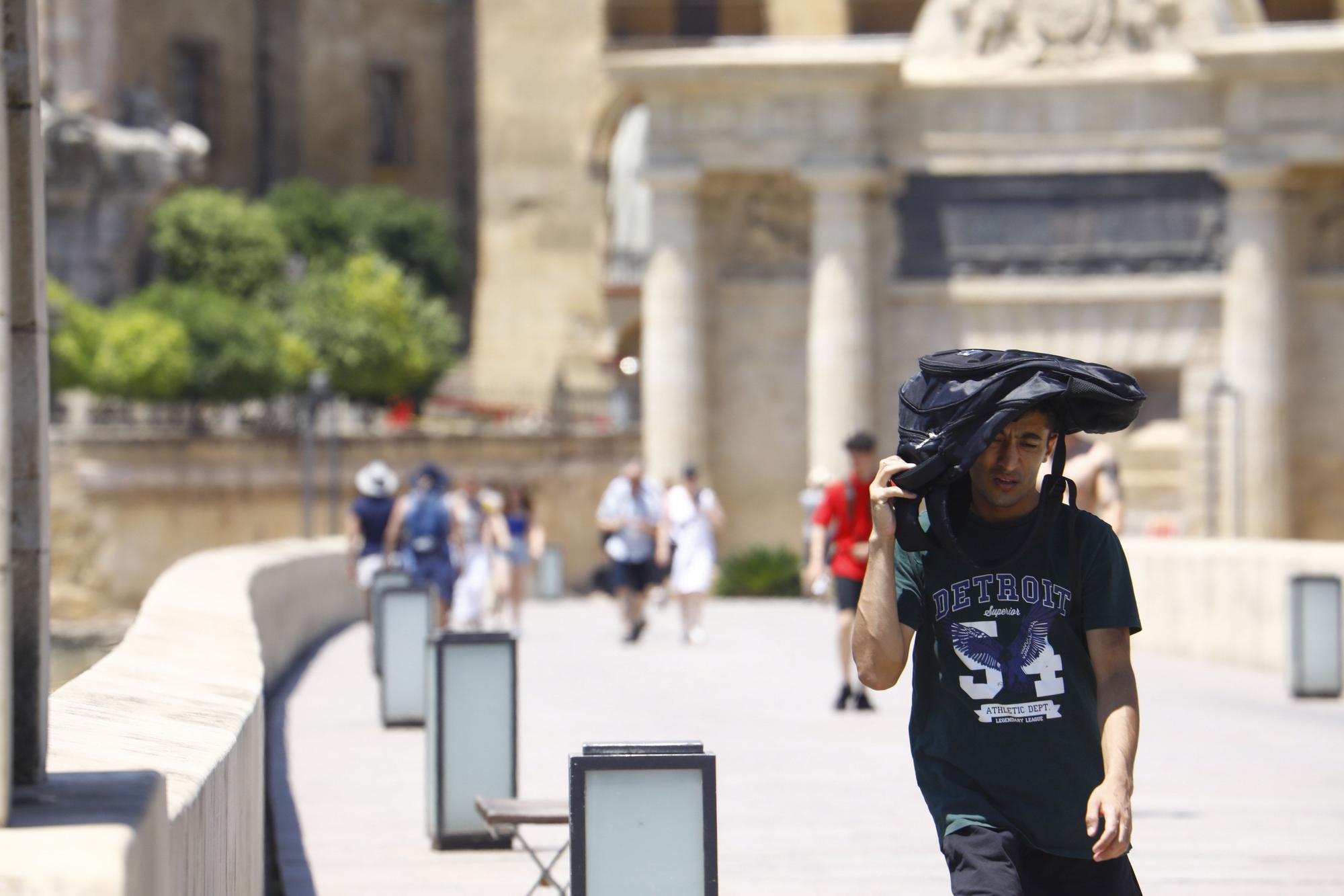 Un turista se protege del sol con una mochila mientras camina por Córdoba, donde está previsto que se alcancen los 40 grados.