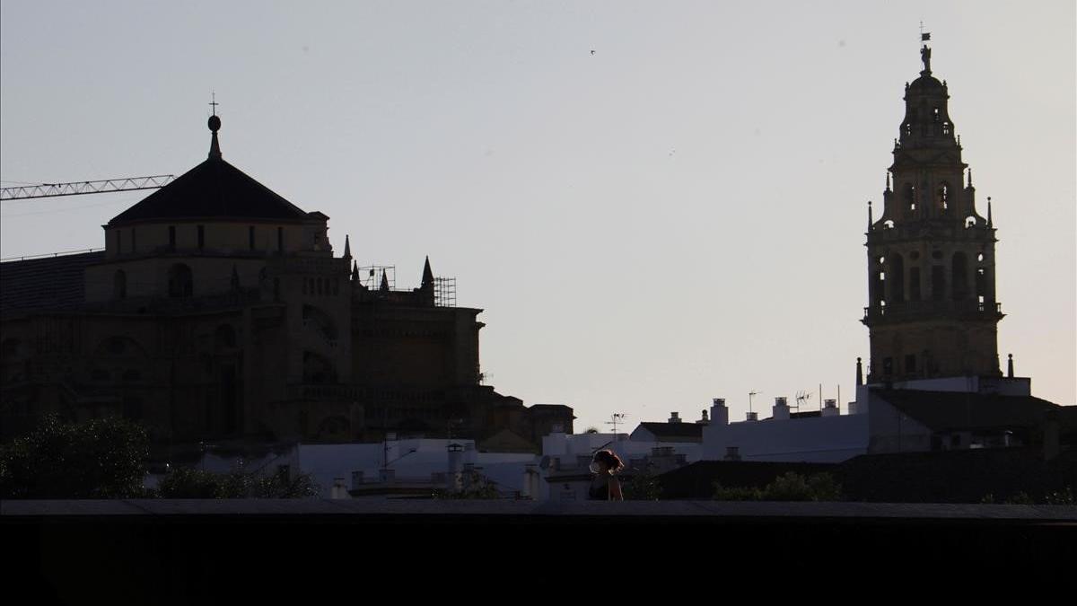 Una mujer protegida con mascarilla camina por uno de los puentes de Córdoba, en las inmediaciones de la mezquita