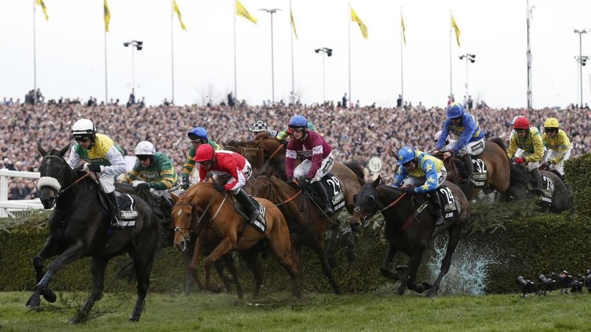 Rule The World, montado por un jockey con chaquetilla roja, supera uno de los obstáculos en el espectacular Grand National.