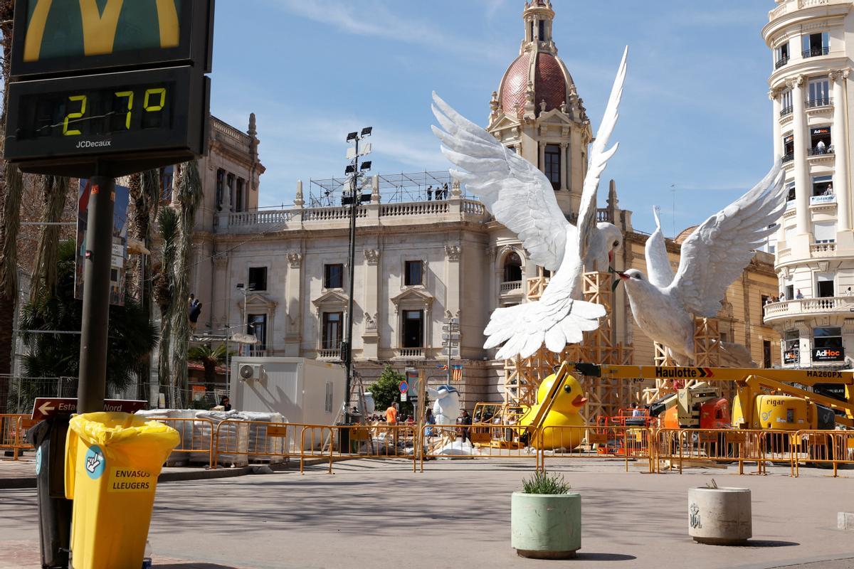 A sign displays temperature with Ninots or giant figures, depicting doves of peace fighting over an olive branch by artist Escif, in the streets before being burned during the traditional annual Fallas festival, in Valencia, Spain, March 15, 2024. REUTERS/Eva Manez