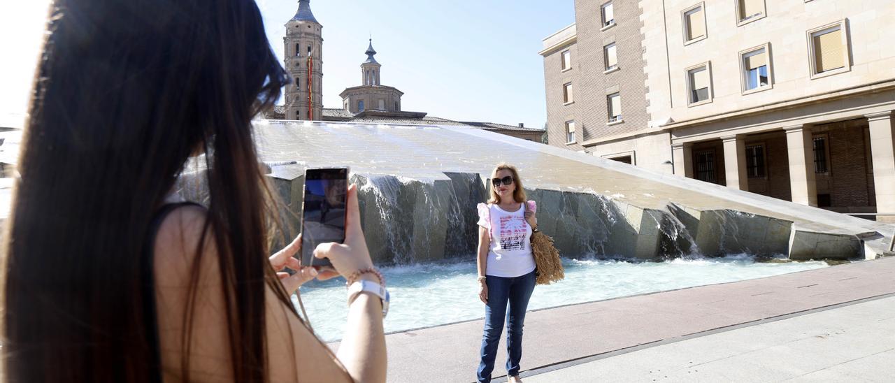 Dos turistas haciendo fotos en la plaza del Pilar de Zaragoza.