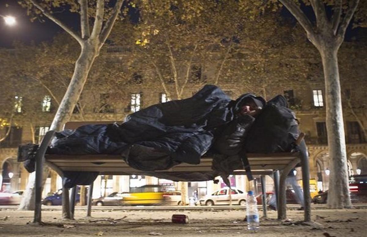 Una persona sense sostre dorm en un banc al costat de la Ciutadella.