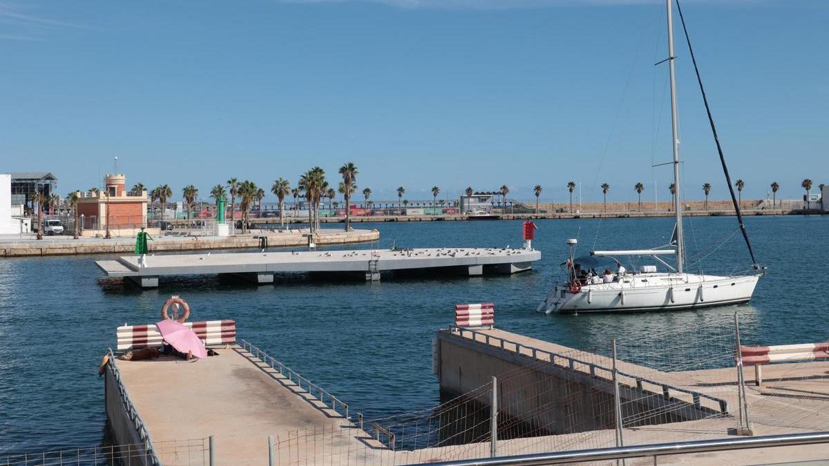 Una embarcación pasando por delante de la isla flotante del Puerto de Alicante.
