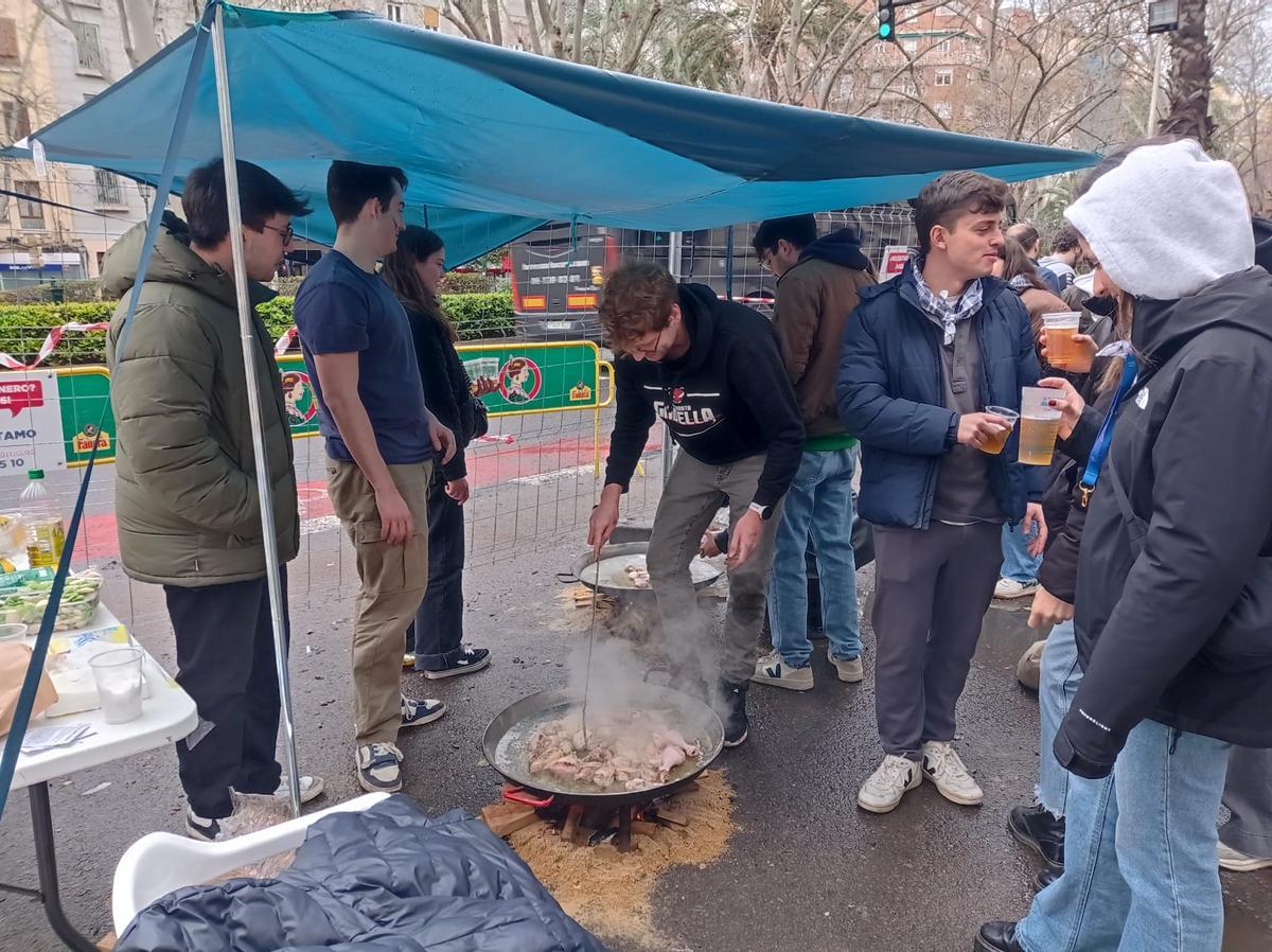 Los chavales de Falla Fernando el Católico-Erudito Orellana cocinan la tradicional paella bajo un toldo improvisado.