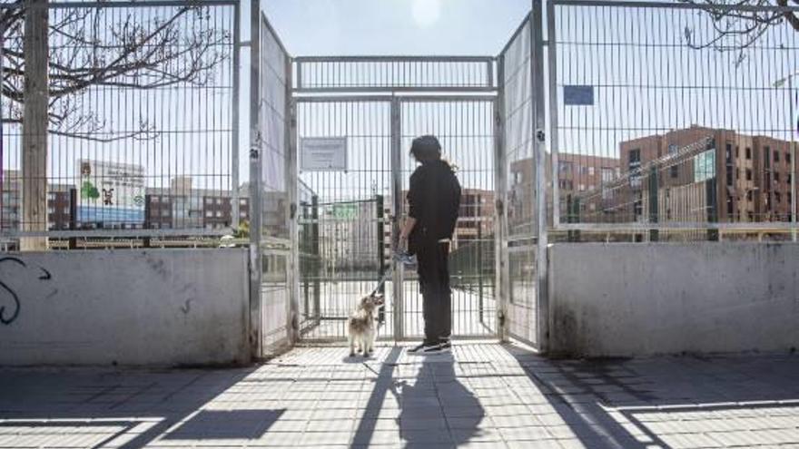 Una usuaria observa el cartel que anuncia el cierre del parque canino, situado en el barrio de Garbinet.