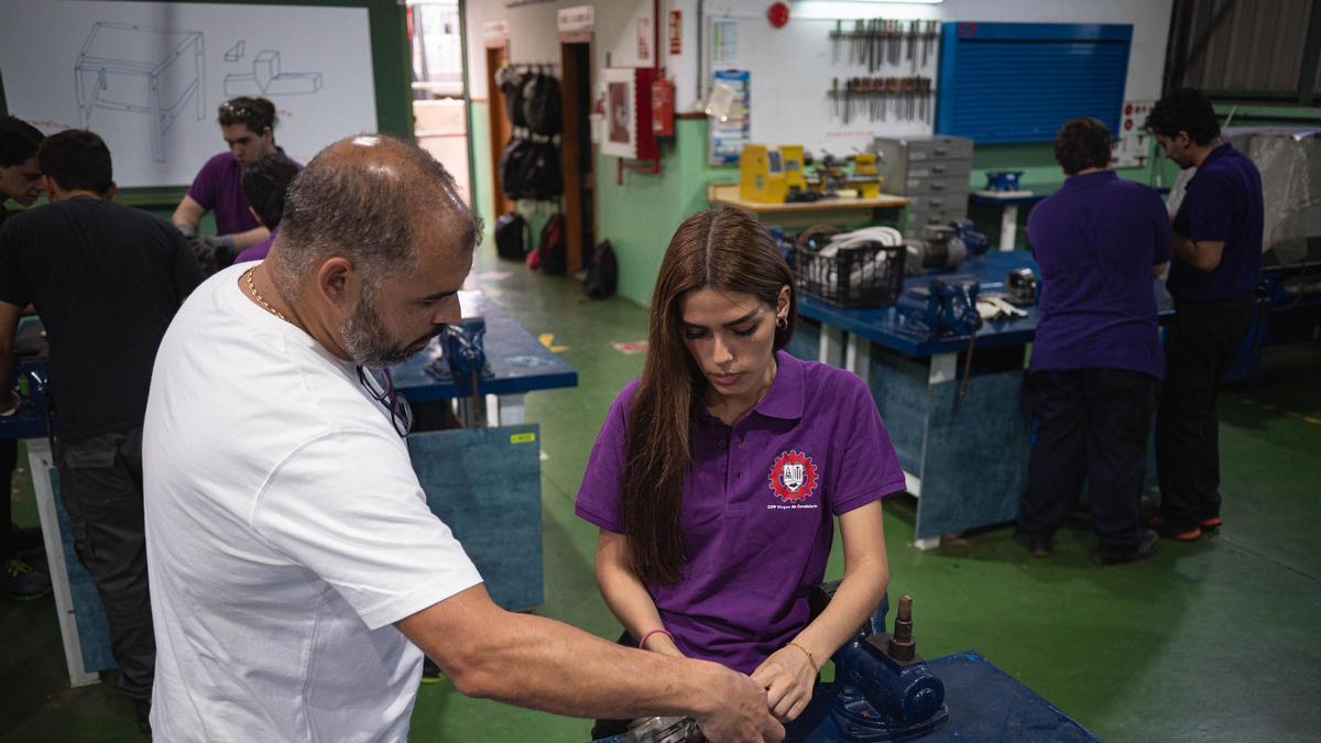 Un profesor explica una práctica a una alumna de FP