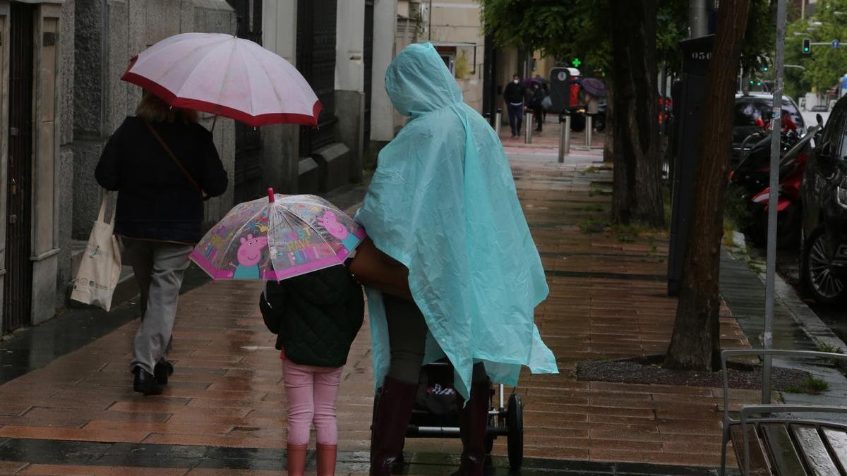 Una mujer y una niña pasean con paraguas.