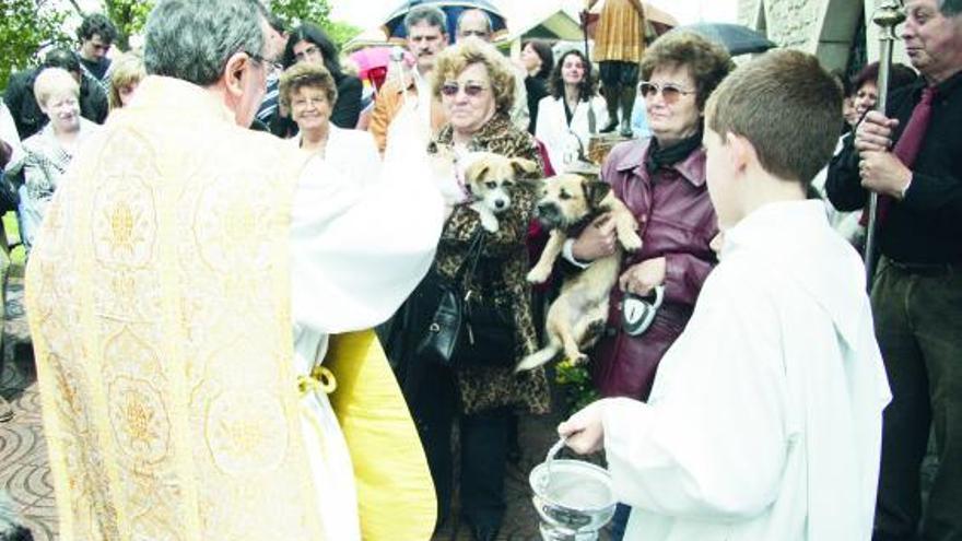 Varios asistentes al acto sostienen sus mascotas durante la bendición, con la imagen de San Isidro detrás.