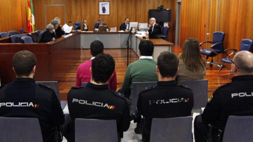 Imagen de los tres acusados en el juicio y los cuatro policías que los custodian.