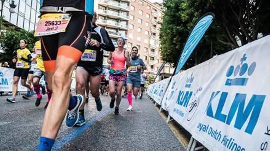 Varios corredores pasan por la calle Colón durante un medio maratón.