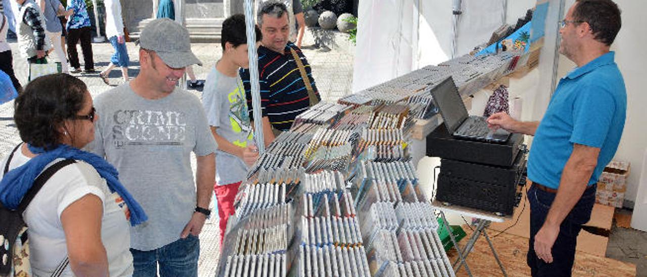 Miguel Noda (dcha.) atiende a varios clientes en el punto de venta de la Feria de Autores Canarios en San Telmo.