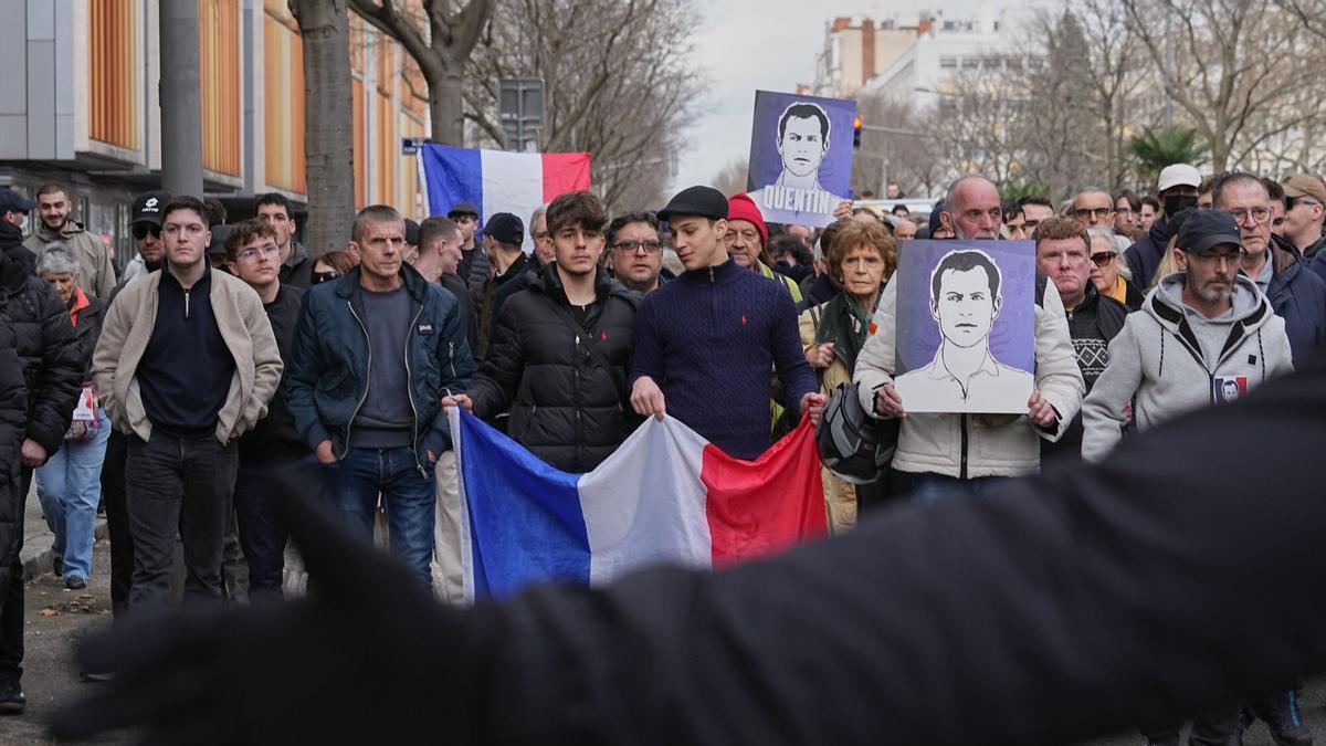 La gente participa en una marcha con banderas nacionales francesas y retratos del estudiante asesinado en Lyon.