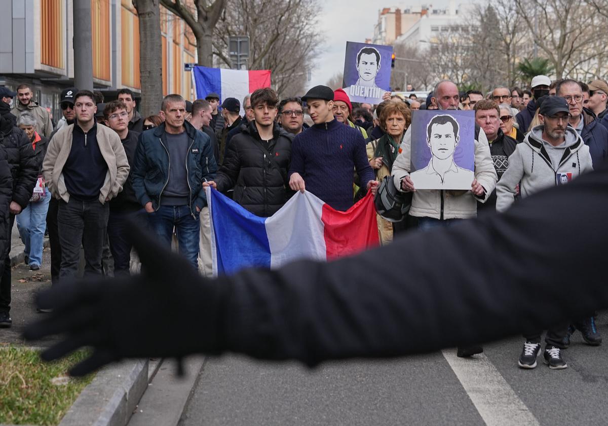 La gente participa en una marcha con banderas nacionales francesas y retratos del estudiante asesinado en Lyon.