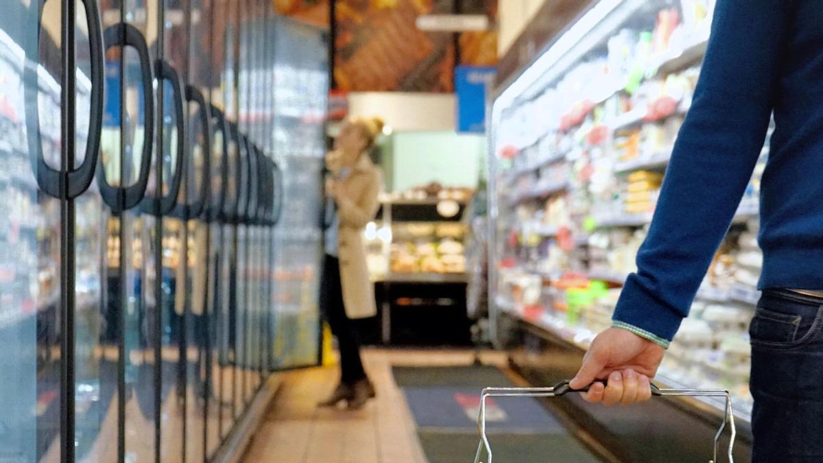 Gente comprando en un supermercado con la cesta de la compra