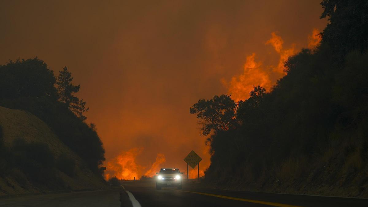 El incendio de Line se extiende por la autopista 330 mientras un vehículo circula cerca de Running Springs en California.