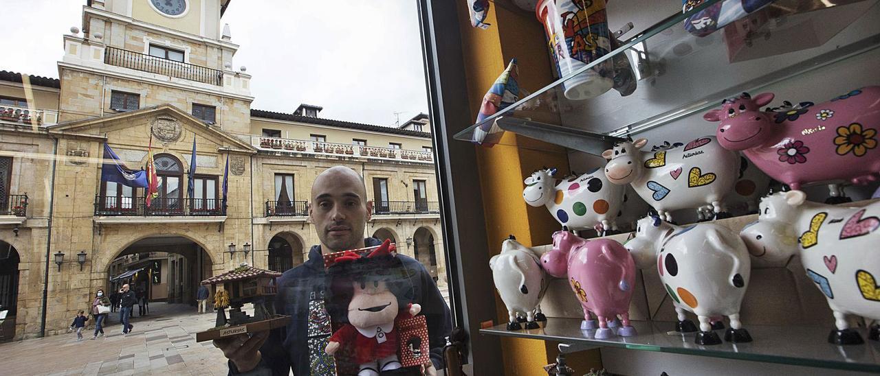 Pedro Arias, trabajador de una tienda de recuerdos, con sus productos. |