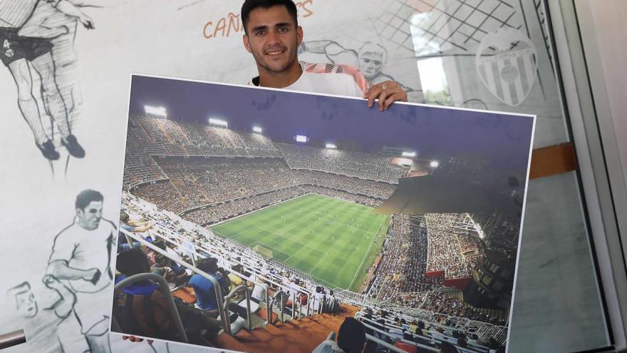 El delantero del Valencia CF Maxi Gómez posa con una foto de Mestalla.